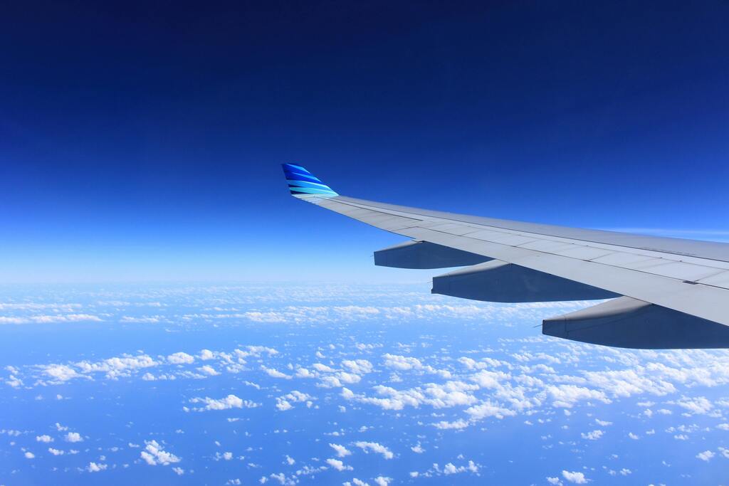 An aircraft wing above the clouds, seen from a cabin window