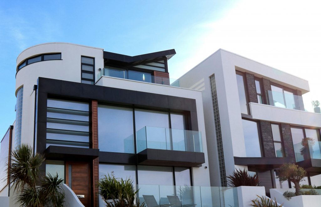 Two modern white houses with large windows and glass balconies